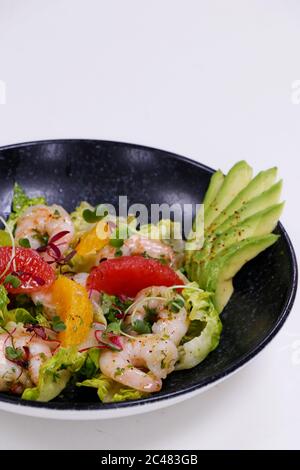 Salat mit Avocado und Garnelen in der Schüssel, Draufsicht, Kopierraum, schwarzer Hintergrund Stockfoto