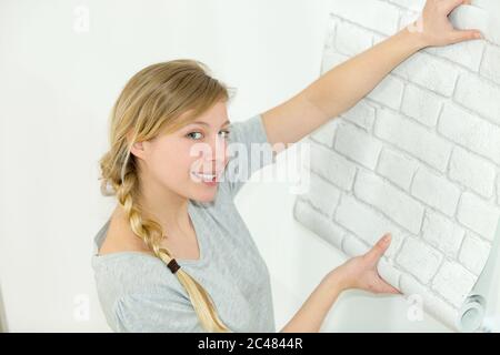 Frau klebt Tapete zu Hause Stockfoto