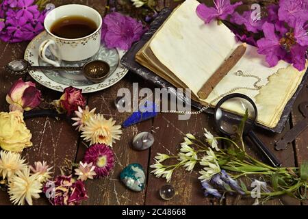 Stillleben mit offenem Tagebuch, Tasse Kaffee und Kristallstein auf Hexentisch. Esoterischer, wicca und okkulter Hintergrund mit magischen Objekten Stockfoto