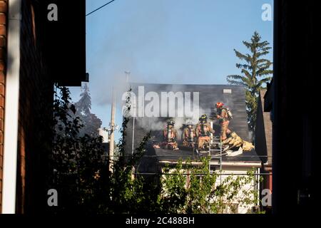 Feuerwehrleute mit Äxten, Fensterbrände brechen Haus Feuer unterwegs. Feuerwehrleute auf dem Dach des Hauses auf Feuer arbeiten, um den Brand zu halten. Feuerwehrmann mit Achsen t Stockfoto