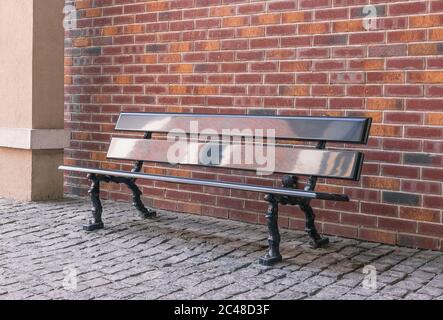 Leere Bank im Vintage-Stil an der Pave Street vor der Red Brick Wall Stockfoto