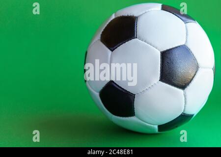 Sport, Fußball, Wettkämpfe, Körperkultur, gesundes Lifestyle-Konzept - Nahaufnahme klassischer Fußball-Lederball in Schwarz und Weiß auf einem schlichten Grün Stockfoto