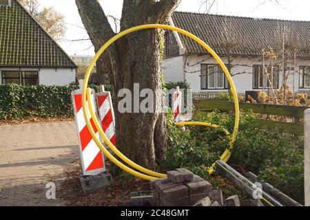 Straßenarbeiten auf der Straße. Eine gelbe Pfeife, ein Baum, Pflastersteine und Straßenschilder. November, Bergen, Niederlande. Stockfoto