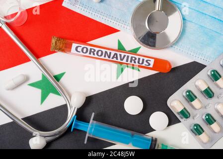 Coronavirus, nCoV-Konzept. Draufsicht schützende Atemmaske, Stethoskop, Spritze, Pillen auf der Flagge Syriens. Ein neuer Ausbruch der chinesischen Coronav Stockfoto