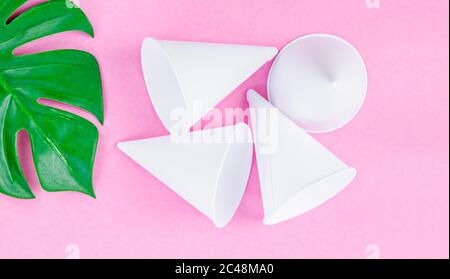 Einweg-Papier Konus Wasserbecher mit grünem Blatt auf rosa Hintergrund. Stockfoto