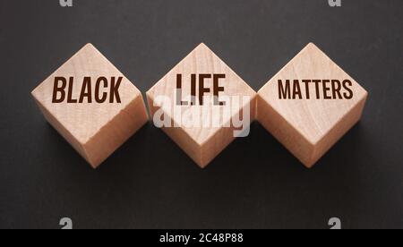 Text von BLM bedeutet, dass schwarze Leben Materie auf Holzblöcken auf schwarzem Hintergrund geschrieben Stockfoto