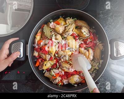 Traditionelle Küche auf einem Glaskeramik-Kochfeld mit einigen Hähnchenflügeln, Draufsicht und leerem Kopierraum für den Text der Redaktion. Stockfoto