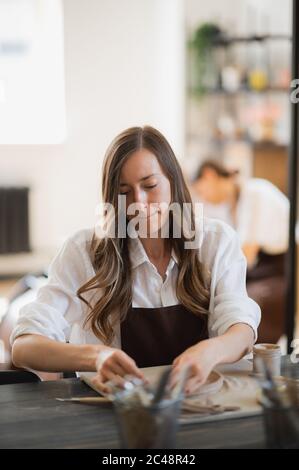 Nahaufnahme von erfahrenen Handwerker Entfernen Teil des Tones während der Herstellung keramischen Produkt in Töpferei Stockfoto