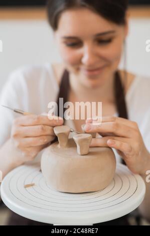 Nahaufnahme des weiblichen Töpfers, der Stock hält und Ornament auf Steingut macht. Clay Master Formung Clay Produkt. Konzept der keramischen Kunst und Hobby. Stockfoto