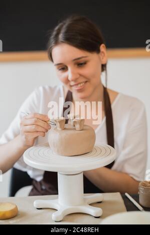 Weibliche Hände halten Stock und machen Ornament auf dekoratives Produkt. Clay Master Formen Ton auf einer Keramik-und Keramik-Werkstatt. Stockfoto