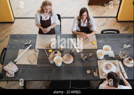 Töpferinnen während des Arbeitsprozesses in der Tonwerkstatt. Frau Meister bereiten Keramik-und Ton-Produkte an großen Holztisch Stockfoto