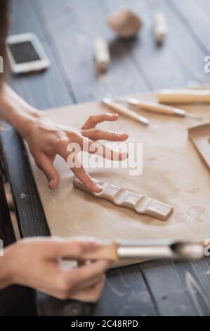 Nahaufnahme von erfahrenen Handwerker Entfernen Teil des Tones während der Herstellung keramischen Produkt in Töpferei Stockfoto