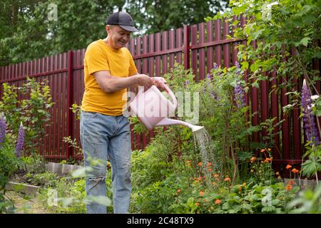 Mann wässert Blumen mit Dose in seinem Garten. Stockfoto