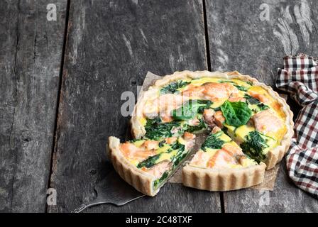 Lachs und Spinat Quiche auf rustikalem Holztisch Stockfoto