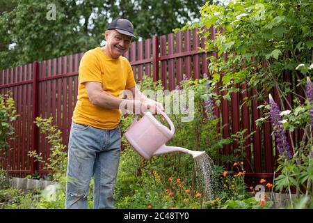 Mann wässert Blumen mit Dose in seinem Garten. Stockfoto