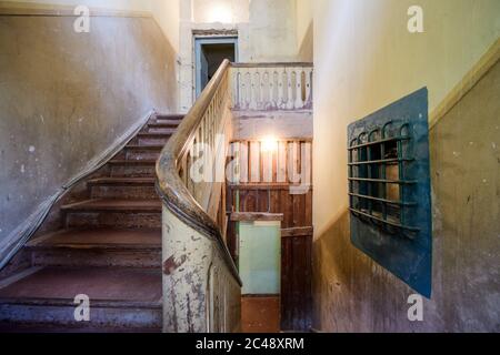 24. Juni 2020, Brandenburg, Potsdam: Die Treppe des ehemaligen Pfarrhauses und rechts das Balkenfenster einer Häftlingszelle im Ausstellungsbereich der Gedenkstätte und Begegnungsstätte Leistikowstraße. Bis zur Auflösung des KGB 1991 wurden Tausende von Männern und Frauen im Geheimdienstgefängnis im Zentrum der sowjetischen "Militärstadt Nr. 7" festgehalten. In der ersten Nachkriegszeit wurden auch Deutsche inhaftiert, später nur sowjetisches Militär und Zivilisten. Im ehemaligen Zentralgefängnis der sowjetischen Spionageabwehr, eine ständige Ausstellung von Fotografien, Original obj Stockfoto