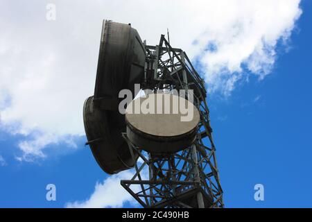 Hohe große Antennen senden Signale mit aktuellen Satellitenschüsseln und hochintensiven elektrischen Kabeln und blauen Himmel mit Wolken Stockfoto