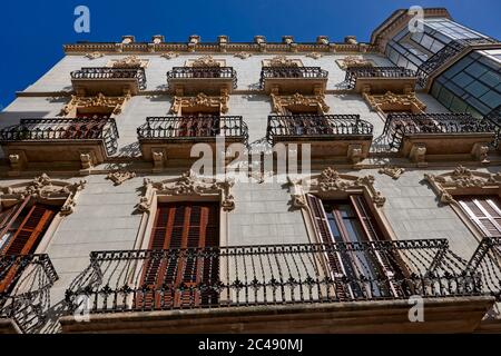 Balkone mit kunstvollen schmiedeeisernen Einzäunungen auf dem alten mehrstöckigen Wohngebäude in Reus, Katalonien, Spanien. Stockfoto