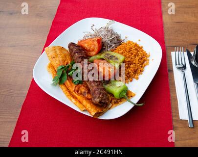 Türkische Adana Kebap mit Bulgur Pilaf und Gemüse auf EINEM Teller serviert Stockfoto