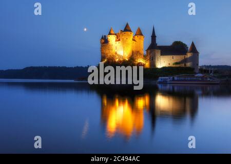 Chateau de Val in Auvergne, Frankreich bei Dämmerung mit Halbmond, der sich im stillen Wasser des ihn umgebenden künstlichen Sees spiegelt. Stockfoto