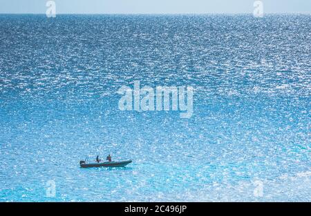 Entferntes Motorboot mit zwei Personen darin auf der glitzernden Oberfläche des Meeres. Luftaufnahme. Stockfoto