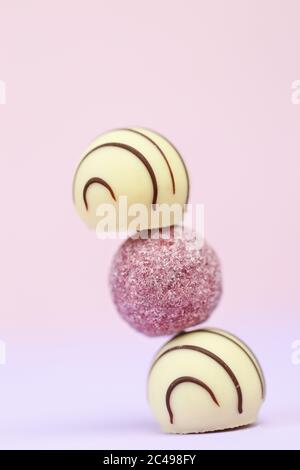 Weiße und rosa Milchschokolade Süßigkeiten Reihe auf einem verschwommenen rosa-lila Pastellhintergrund.verschiedene Schokolade.Süße köstliche Desserts Stockfoto