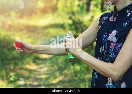 Frau sprüht Mücke und Zeckenschutz auf Arm im Wald Stockfoto