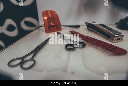 Barbier-Shop-Ausrüstung am Schreibtisch. Professionelle Friseurwerkzeuge. Elektrische Rasiermesser, Kamm und Schere Stockfoto