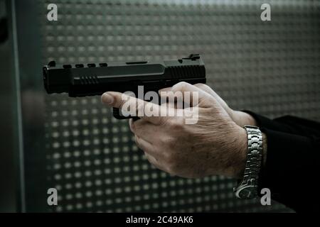 Mann mit Pistole auf Ziel in Indoor-Schießstand oder Schießstand.Nahaufnahme Pistole und Hände. Stockfoto