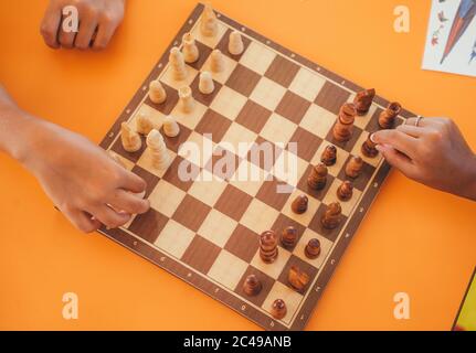 Ausgeschnittene Aufnahme von jungen Mann und Frau, die Schach spielen.Draufsicht auf zwei Personen, die Schach spielen. Nahaufnahme von Schachbrett und Händen. Stockfoto