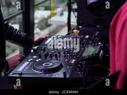 DJ Sound Control Konsole zum Mischen von Tanzmusik und Laptop in Disco Club. Hände berühren Tasten Schieberegler, spielen elektronische Musik auf Mischdeck, col Stockfoto