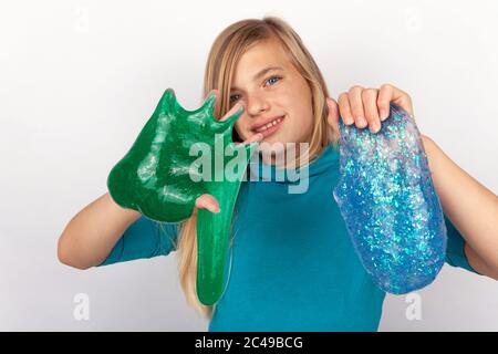 Mädchen hält einen grünen und einen blauen Glitzer Schleim Stockfoto