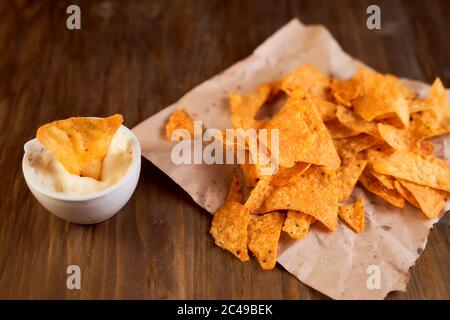 Mexikanische Mais Chips Nachos liegen auf einem Holztisch. Eine Sache in einer Schüssel mit Sauce Stockfoto