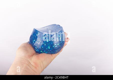 Hand hält einen geformten blauen Glitzer Schleim Stockfoto