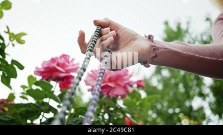 Frau beleuchtet Hand Nahaufnahme zählt Rosenkranz - Malas Stränge von Edelsteinen Perlen für Zählung während Mantra Meditationen verwendet. Mädchen sitzt auf Sommer Natur Stockfoto