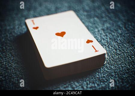 Ein Deck mit neuen Karten auf einem grauen Plüschtisch, zuerst Herz-Ass. Stockfoto