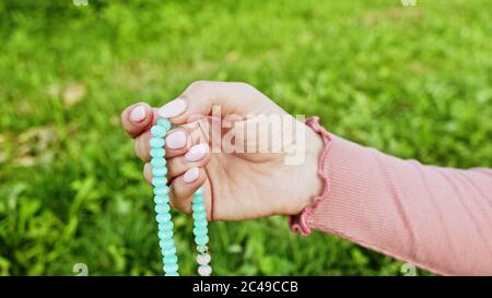 Frau beleuchtet Hand Nahaufnahme zählt Rosenkranz - Malas Stränge von Edelsteinen Perlen für Zählung während Mantra Meditationen verwendet. Mädchen sitzt auf Sommer Natur Stockfoto