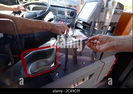 Dormagen, Deutschland. Juni 2020. Bei einer Pressekonferenz der Deutschen Bahn passiert eine Hand eine Banknote durch eine Plexiglasscheibe, die den Fahrersitz eines Busses vom Fahrgastraum trennt. Während der Cornoa-Pandemie sollen Trennscheiben dieser Art sukzessive im Fahrerarbeitsplatz der gesamten DB-Busflotte installiert werden. Quelle: Henning Kaiser/dpa/Alamy Live News Stockfoto