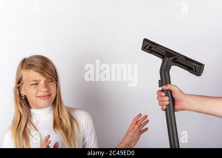 Mädchen weigert sich, eine Hand mit einem Staubsauger Bodenwerkzeug. Childre hasse Hausarbeit Konzept. Stockfoto