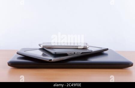 Stapel von elektronischen Geräten auf einem Tisch - Notebook, Tablet, eBook-Reader und ein smatphone auf der Oberseite Stockfoto