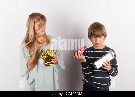 Kinder schockiert von seltsamen Geschenken. Die vorliegenden Kisten enthalten Apfel und Paprika. Stockfoto