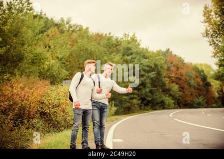 Hexerei Geste. Beginnen Sie mit dem Wandern ein tolles Abenteuer in Ihrem Leben. Firmenfreunde Reisende, die auf dem Naturhintergrund der Straße hitchwandern. Reisende auf dem Weg. Freunde, die hitchhitchhamps unterwegs Stockfoto