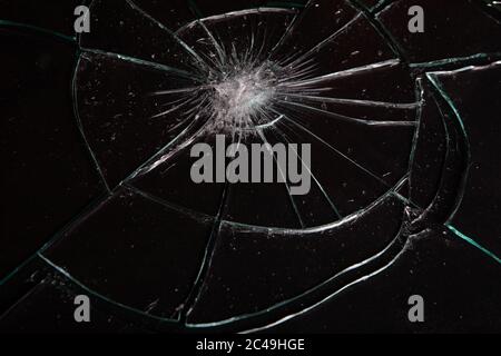 Zerbrochenes Glas mit Rissen auf schwarzem Hintergrund Stockfoto