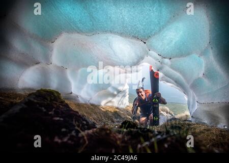 Der Skifahrer Andy Meldrum, Inhaber des Glencoe Mountain Resort, blickt in einen Schneetunnel, der sich unter einem der verbleibenden Schneepatches auf den Hängen von Meall A'Bhuiridh in Glencoe bildet, da der Donnerstag der heißeste Tag des Jahres in Großbritannien sein könnte, da die Temperaturen noch weiter steigen werden. Stockfoto