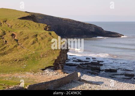 Die gut erodierten Felsen und der leere Strand bilden die Klippe bei Dunraven oder Southerndown Bay mit einer Flut an einem schönen Tag während der Absperrung. Stockfoto