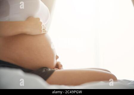 Schöner Bauch der schwangeren Frau mit ihren Händen darauf Stockfoto
