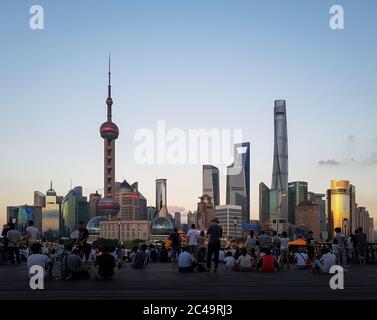 Shanghai, China - Skyline der Pudong New Area. Der Bund, oder Waitan, Uferbereich über den Huangpu Fluss. Menschen genießen den Sonnenuntergang und Wolkenkratzer. Stockfoto