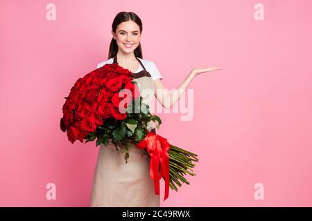 Foto von attraktiven freundlich floral Shop Assistentin Dame fröhlich Stimmung halten hundert Rosen Bündel niedrigen Preis offen Arm tragen Schürze T-Shirt isoliert Stockfoto