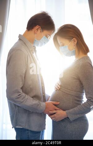 Sonniger Tag zu Hause von schwangeren jungen Paar in Quarantäne Stockfoto