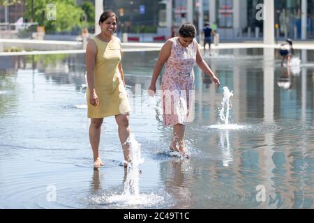 Zwei Frauen, die durch seichte Wasserbrunnen laufen, Sommer, Centenary Square, Birmingham UK Stockfoto